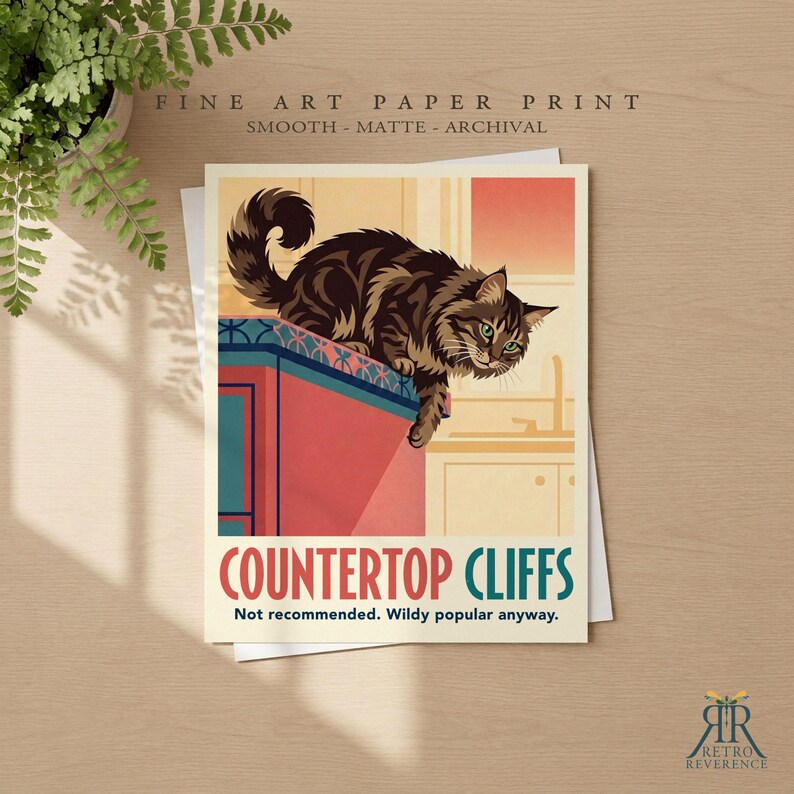 May include: A fine art paper print featuring a brown tabby cat perched on the edge of a red kitchen counter. The text reads: FINE ART PAPER PRINT, COUNTERTOP CLIFFS, Not recommended. Wildy popular anyway. The print has a smooth matte finish.
