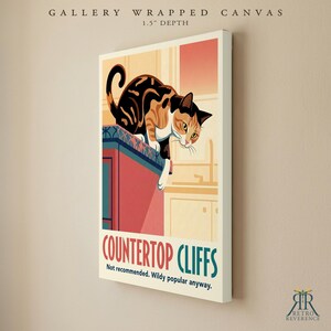 May include: A gallery wrapped canvas with a 1.5 inch depth featuring a calico cat perched on a kitchen counter. The print includes the text "GALLERY WRAPPED CANVAS", "COUNTERTOP CLIFFS", and "Not recommended. Wildy popular anyway."
