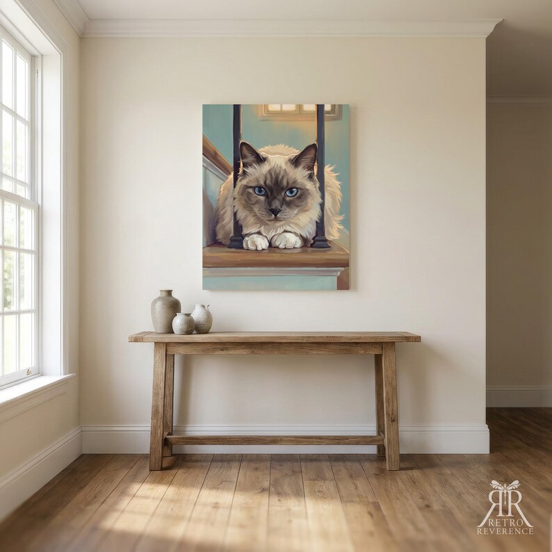 May include: A rectangular wall art print featuring a fluffy cream and brown cat with striking blue eyes, positioned between two dark vertical railings on a wooden staircase. The cat has a pointed face and white paws, rendered in a painterly style.