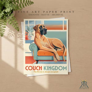 Puede incluir: Una impresi&oacute;n art&iacute;stica en papel que muestra a un gran dan&eacute;s de color canela descansando en un sof&aacute; verde azulado con cojines naranjas. El texto dice COUCH KINGDOM y The throne is always occupied. Impresi&oacute;n lisa, mate y de archivo.