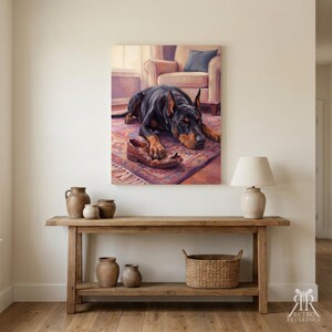 May include: A wall art print featuring a black and tan Doberman dog lying on a patterned rug with a brown leather shoe between its paws. The scene includes a soft-toned armchair in the background, rendered in a painterly style with warm lighting.