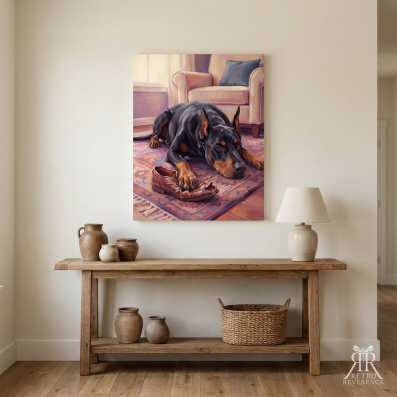 May include: A wall art print featuring a black and tan Doberman dog lying on a patterned rug with a brown leather shoe between its paws. The scene includes a soft-toned armchair in the background, rendered in a painterly style with warm lighting.