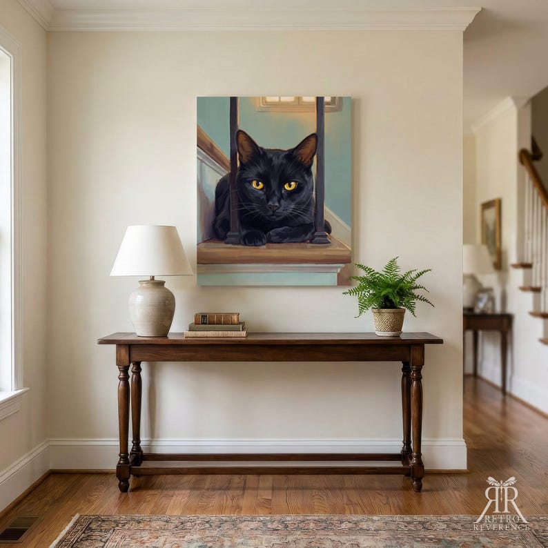 May include: A square canvas wall art print featuring a black cat with bright yellow eyes resting on a wooden staircase landing between dark vertical railings. The painting is displayed on a light-colored wall above a wooden console table.