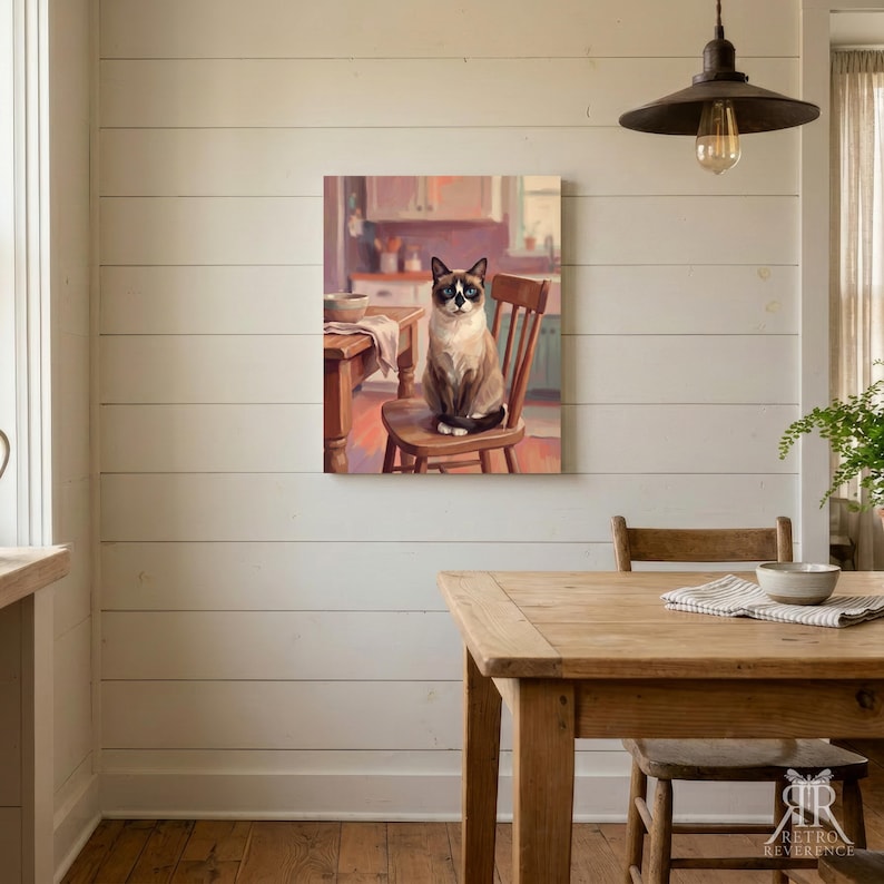 May include: A rectangular wall art print depicting a Siamese cat with blue eyes sitting on a wooden chair in a kitchen setting. The cat has dark brown points on its ears, face, and paws, with a light cream-colored body. A wooden table is visible.