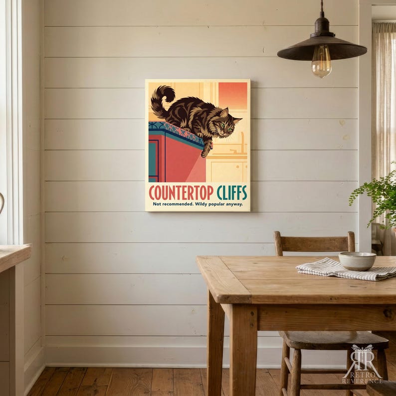 May include: A rectangular wall art print featuring a brown tabby cat perched on the edge of a red kitchen counter. The text reads COUNTERTOP CLIFFS and Not recommended. Wildy popular anyway. The background shows a kitchen interior in warm tones.