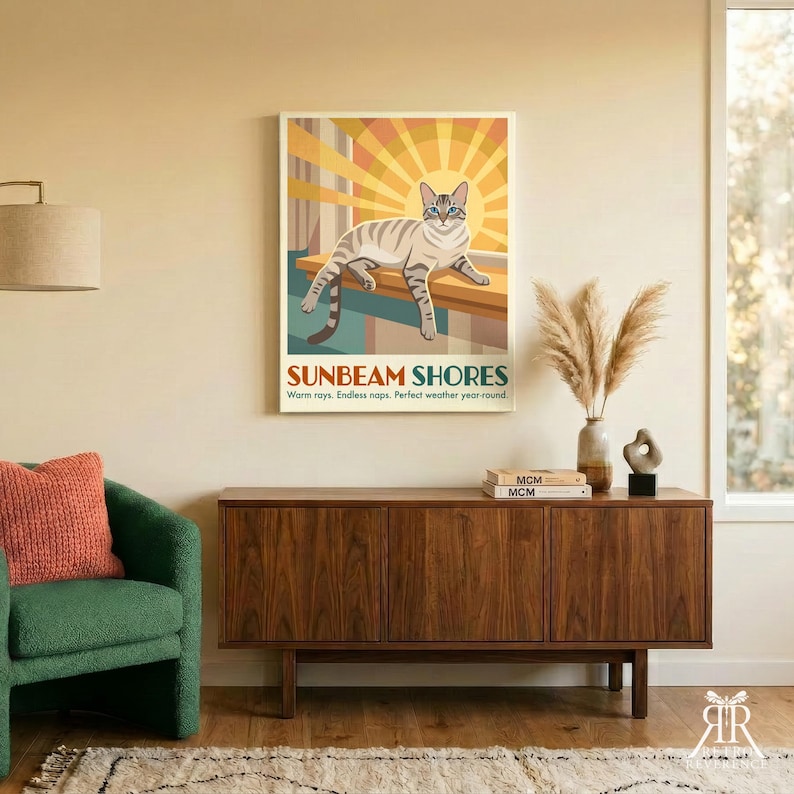May include: A rectangular wall poster titled SUNBEAM SHORES featuring a light brown tabby cat resting on a ledge against a yellow and orange sunburst background. The text reads: SUNBEAM SHORES. Warm rays. Endless naps. Perfect weather year-round.