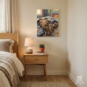 Puede incluir: Una impresi&oacute;n de arte mural que muestra a un gato atigrado marr&oacute;n y esponjoso acostado boca arriba dentro de una maleta abierta llena de ropa doblada. El gato est&aacute; sobre una cama con almohadas y una colcha, con una ventana visible al fondo.