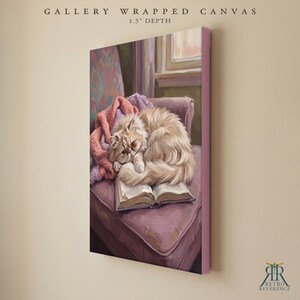 May include: A gallery wrapped canvas with a 1.5 inch depth featuring a painting of a fluffy cream-colored cat curled up asleep on an open book. The cat rests on a mauve armchair draped with a pink knitted blanket, with a window visible in the background.