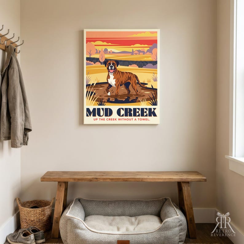 May include: A rectangular wall art print featuring a brindle boxer dog standing in a muddy puddle. The background shows a stylized landscape with a sunset sky. The text reads MUD CREEK and UP THE CREEK WITHOUT A TOWEL in dark blue and red.