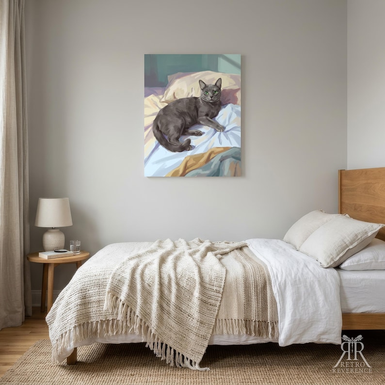 May include: A rectangular wall art print featuring a digital illustration of a grey cat lying on rumpled white and light blue bedding with a soft pink pillow behind it. The cat has green eyes and is positioned in the center of the composition.