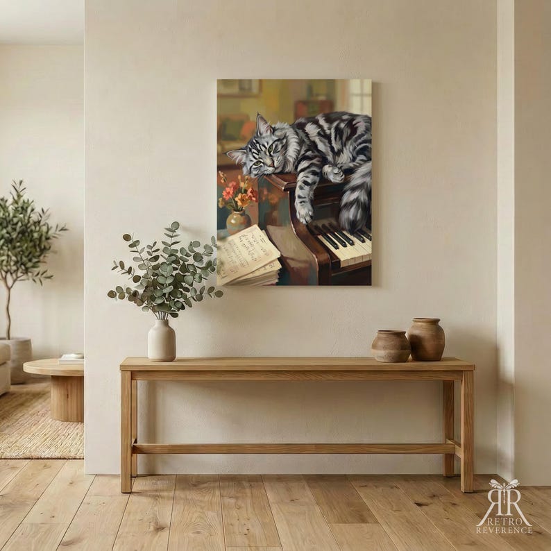 May include: A rectangular wall art print featuring a grey and black tabby cat resting on a brown wooden piano. Beside the cat are orange flowers in a small vase and a stack of sheet music. The artwork is displayed in a room with a wooden console table.