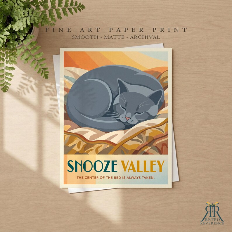 May include: A fine art paper print featuring a graphic illustration of a grey cat curled up on a patterned blanket. The text reads SNOOZE VALLEY and THE CENTER OF THE BED IS ALWAYS TAKEN. The print is smooth, matte, and archival quality.