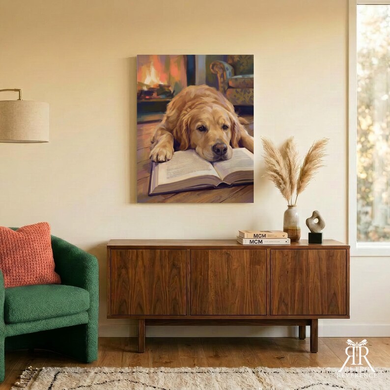 May include: A rectangular wall art print featuring a golden retriever resting its head on an open book. The dog has light brown fur and is positioned in front of a warm, glowing fireplace. The artwork is displayed in a room with a wooden sideboard.