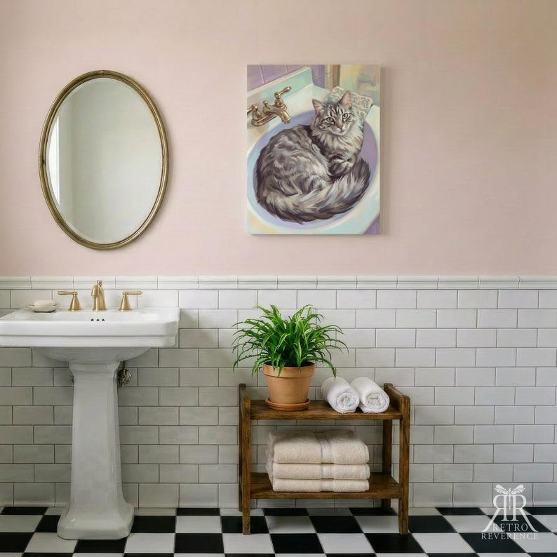 May include: A rectangular wall art print featuring a grey tabby cat curled inside a bathroom sink. The artwork is displayed in a bathroom with a white pedestal sink, a gold faucet, a green potted plant, and a wooden shelf with folded towels.