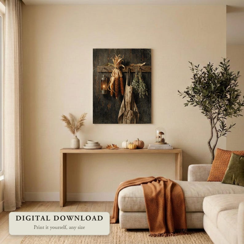 Vintage style still life of dried corn, an apron and herbs hanging by lantern light, hung on a wall in a cozy living room decorated for fall, shown as a digital file you print yourself