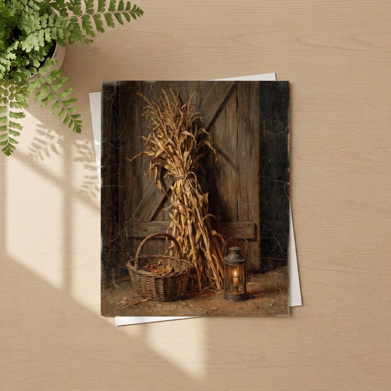 May include: A rectangular print featuring a rustic scene with a bundle of dried corn stalks leaning against a dark wooden door. A woven wicker basket sits on the ground next to a metal lantern with a lit candle inside, creating a warm glow.