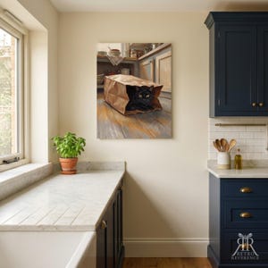 May include: A rectangular wall art print depicting a black cat with bright yellow eyes sitting inside a brown paper grocery bag on a wooden floor, set within a kitchen scene featuring cabinets, a window, and a potted green plant.
