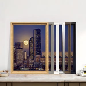 May include: A framed print of a cityscape at night, with a full moon visible above the skyscrapers. The image is displayed in a natural wood frame, with other frame colours including silver, white, brown, and black. A decorative tray with glasses and a bottle is on the right.