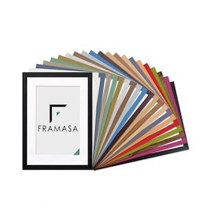 May include: A black rectangular picture frame with a white mount featuring the black text FRAMASA and a geometric logo. Behind the frame, a fan-shaped display showcases a variety of picture frame samples in numerous colours and textures.