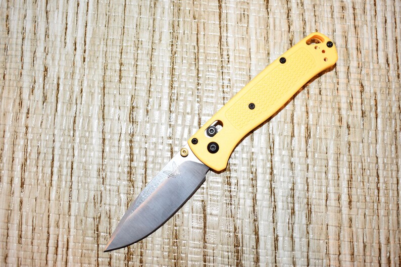 May include: A white ceramic mug with a black handle and the text "But First, Coffee" in a bold, black font. The mug is set against a neutral background, highlighting its simple design.