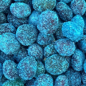 Puede incluir: Primer plano de un montón de caramelos azules, cada pieza está cubierta con una capa de azúcar blanca.