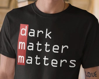 May include: Black t-shirt with white text that reads "dark matter matters" in a bold, sans-serif font. The word "matter" is highlighted in red.