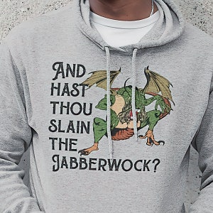 Puede incluir: Una sudadera con capucha gris con una ilustración de un dragón verde y el texto "And hast thou slain the Jabberwock?"