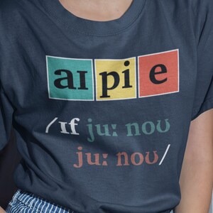 May include: A navy blue t-shirt with a graphic of the word "ai pie" in colorful squares. The text below the graphic reads "/if ju: now ju: now/"