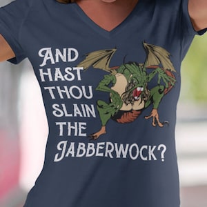 Puede incluir: Una camiseta azul marino con un gráfico blanco de un dragón verde con el texto "And hast thou slain the Jabberwock?"