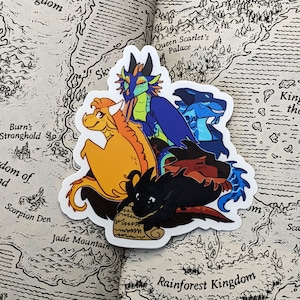 Pode incluir: Um adesivo com cinco drag&otilde;es em v&aacute;rias poses. Os drag&otilde;es s&atilde;o azuis, laranja, preto e vermelho. Os drag&otilde;es est&atilde;o em um fundo branco. O adesivo est&aacute; em um livro com um mapa de um mundo fict&iacute;cio.