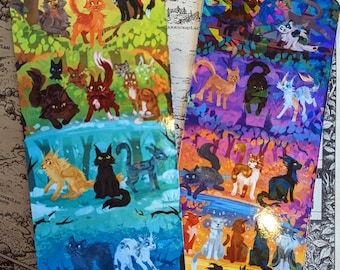 Può includere: Due segnalibri colorati con illustrazioni di gatti. Uno ha uno sfondo verde e blu, l'altro uno sfondo viola e arancione. I gatti sono raffigurati in vari colori, tra cui arancione, nero, bianco e grigio. I segnalibri sono rettangolari.