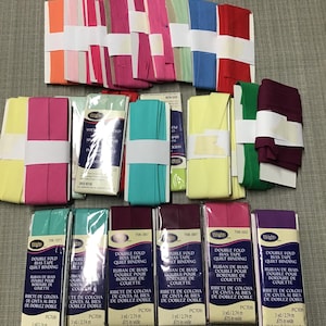 May include: A collection of Wrights double fold bias tape quilt binding packages in various colors including orange, pink, red, blue, green, yellow, and purple. Each package is labeled with 3 yards and 2.74 meters length and .875 inches width.