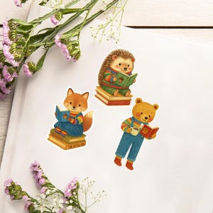 Könnte beinhalten: Drei Aufkleber mit Waldtieren, die Bücher lesen. Ein Fuchs, ein Igel und ein Bär sind in farbenfrohen Outfits dargestellt, jeder sitzt auf einem Stapel Bücher. Der Fuchs-Aufkleber hat den Text "THE LITTLE FOX".