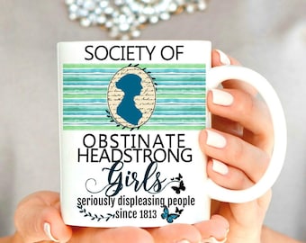 May include: White ceramic mug with the text "SOCIETY OF OBSTINATE HEADSTRONG Girls seriously displeasing people since 1813." The mug features a teal and green striped design and a silhouette of a woman.