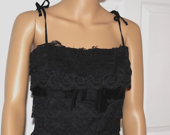May include: A black lace dress with a ruffled neckline and a satin ribbon bow at the waist.