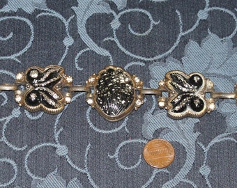 May include: A gold-tone bracelet with black enamel butterfly and round charms. The charms have a sparkly, glittery finish.