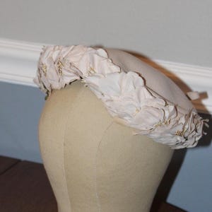 May include: A white hat with a flower design. The hat is made of fabric and has a soft, feminine look.