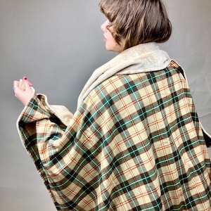 May include: A plaid throw blanket with a cream, brown, and green plaid pattern. The blanket has a soft, plush lining.