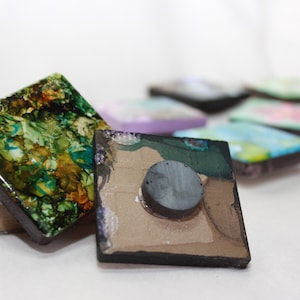 May include: A set of colorful square magnets with abstract designs. The magnets are made of resin and have a black backing with a round magnet on the back.