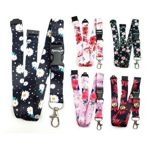 May include: Set of six colourful lanyards with floral patterns. Each lanyard features a black plastic buckle with the word "Spirius" printed on it. The lanyards are approximately 45 cm long.