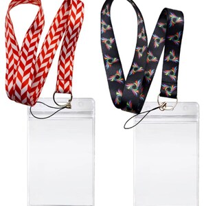 May include: Two clear plastic badge holders with black lanyards. One lanyard has a red and white chevron pattern, the other has a black background with a colourful swirl pattern.