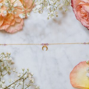 Puede incluir: Un delicado brazalete de cadena dorada con un dije de luna creciente y peque&ntilde;as cuentas moradas.