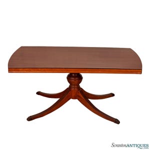 May include: A mahogany-colored, half-moon shaped dining table. The table has a pedestal base with six curved legs. The table's top is 60 inches long and 36 inches wide. The table is a classic piece of furniture.