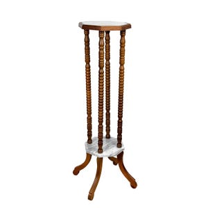 May include: A wooden plant stand with a white marble top and a hexagonal base. The stand has four legs and a decorative, turned design.