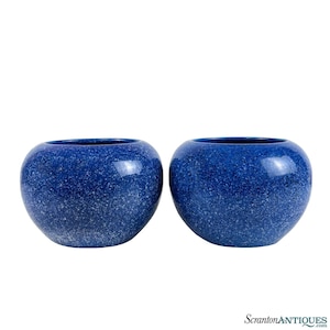 May include: Two blue ceramic planters with a speckled white glaze. The planters are round and have a wide opening.