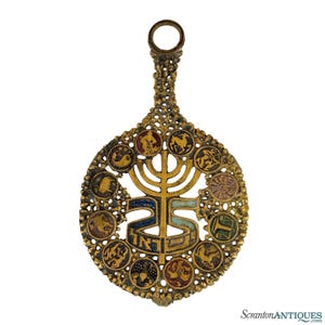 May include: Ornate gold-toned pendant with a central menorah design and Hebrew text. The pendant features a circular shape with a handle and is adorned with small, colorful circular images around the perimeter. The overall design is intricate and detailed.