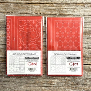 May include: Two rectangular red fabric panels for Sashiko coaster projects, labelled Part 1 and Part 2. Each panel features white printed geometric patterns and includes a label with item numbers CST2021-01A and CST2021-02A, plus fabric size 35cm by 47cm.