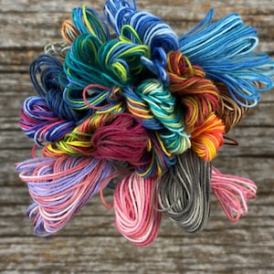 May include: A collection of colorful embroidery floss spools in various shades of blue, green, red, pink, yellow, and gray.