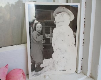 Vintage foto uit de jaren 40 van kind en sneeuwpop - retro foto van kleine jongen in sneeuw - kortstondig