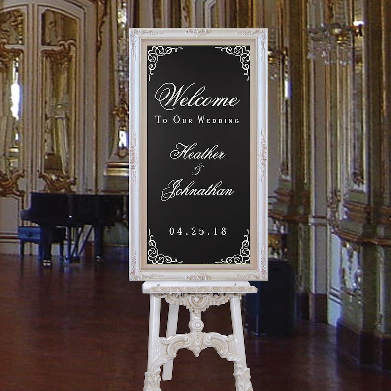 以下が含まれることがあります： 黒い額縁の黒板に「Welcome to our wedding Heather & Johnathan 04.25.18」と書かれた白いイーゼル。